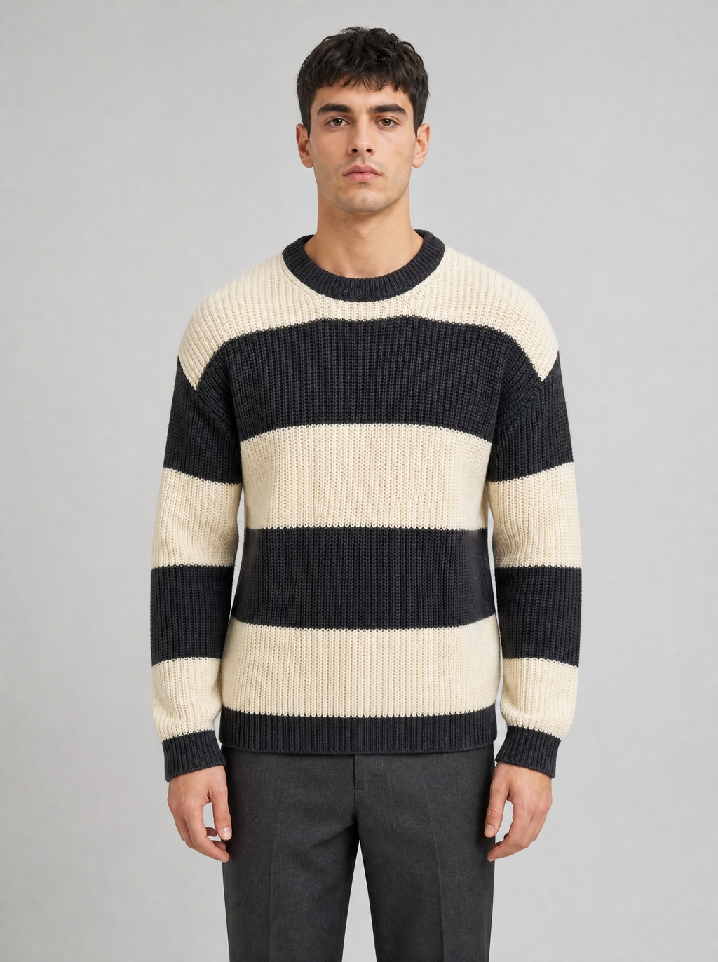 Man wearing a black and cream striped knit sweater, front view on a light grey studio background