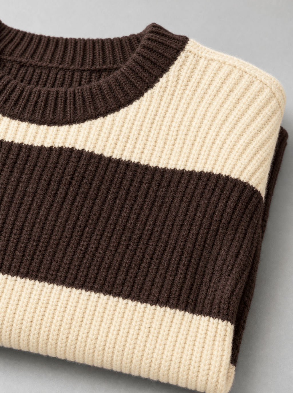 Close up of the ribbed crew neck and wide brown and cream stripes on a knit sweater