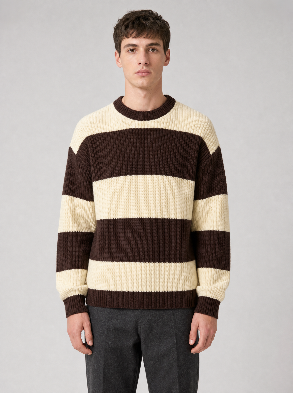 Man wearing a brown and cream striped knit sweater, front view on a light grey studio background