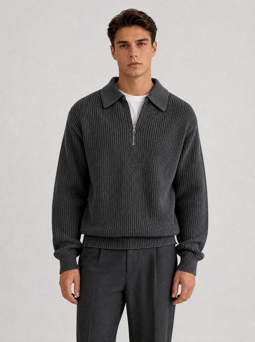 Man wearing a charcoal half zip knit pullover, front view on a light grey studio background