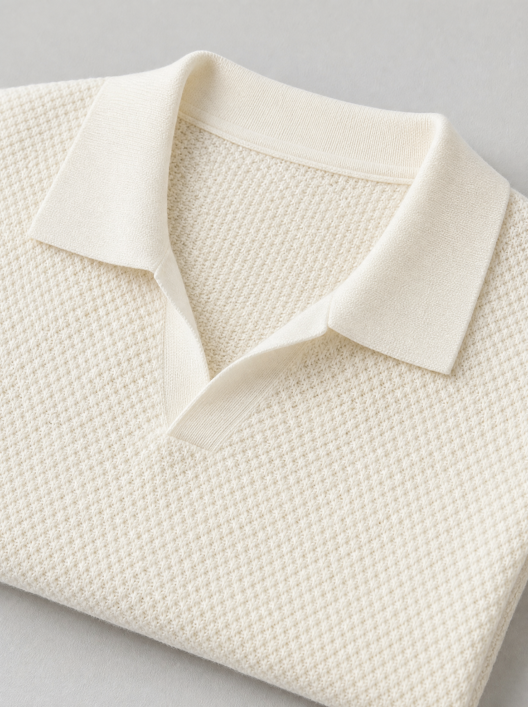 Close up of the open collar and raised knit texture on a cream short sleeve polo