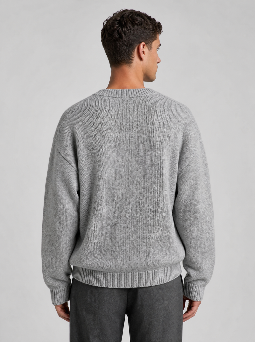 Back view of a light grey oversized knit sweater showing the shoulder line and sleeves
