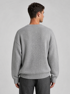 Back view of a light grey oversized knit sweater showing the shoulder line and sleeves