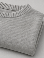 Close up of the wide ribbed crew neck and knit texture on a light grey oversized sweater