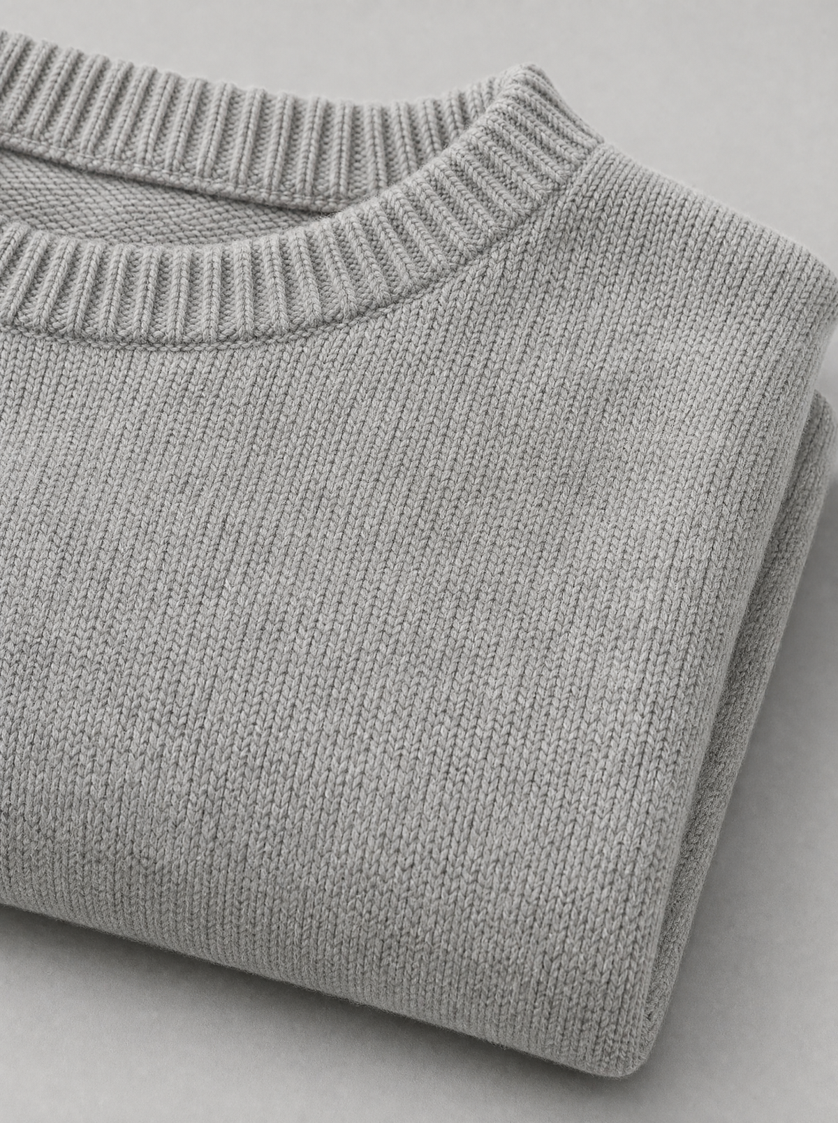 Close up of the wide ribbed crew neck and knit texture on a light grey oversized sweater