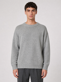 Man wearing a light grey oversized knit sweater, front view on a light grey studio background