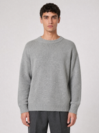 Man wearing a light grey oversized knit sweater, front view on a light grey studio background