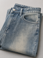 Close up of the waistband, shank button and pocket stitching on loose fit wide leg denim jeans