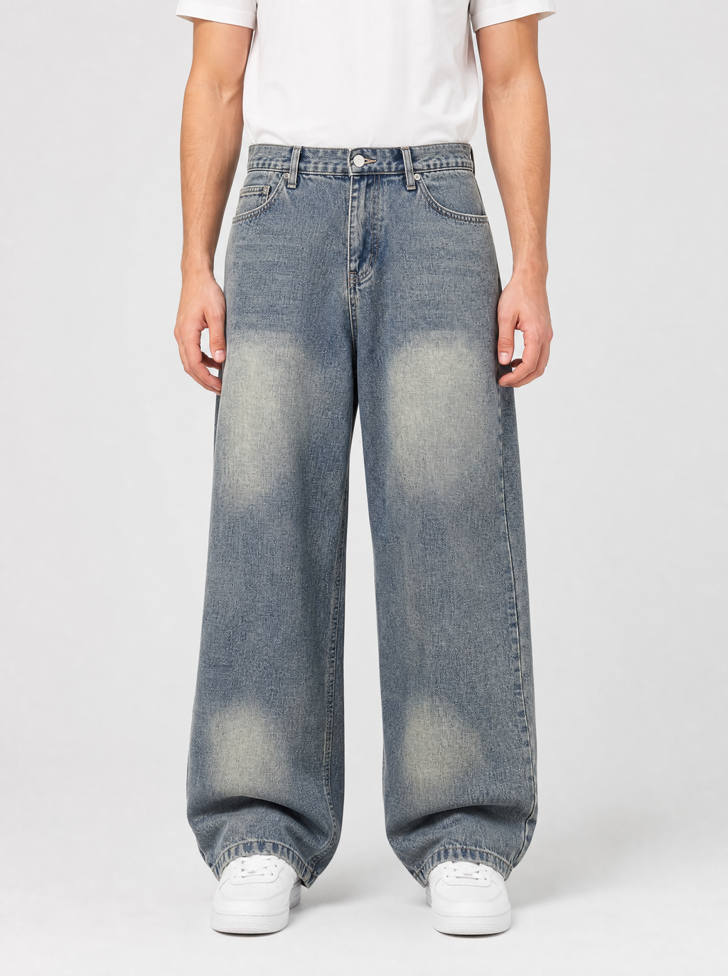 Man wearing loose fit wide leg denim jeans, front view on a light grey studio background
