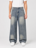 Man wearing loose fit wide leg denim jeans, front view on a light grey studio background