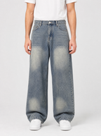 Man wearing loose fit wide leg denim jeans, front view on a light grey studio background