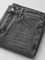 Close up of the waistband, shank button and pocket stitching on oversized baggy washed denim jeans
