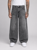 Man wearing oversized baggy jeans in washed denim, front view on a light grey studio background