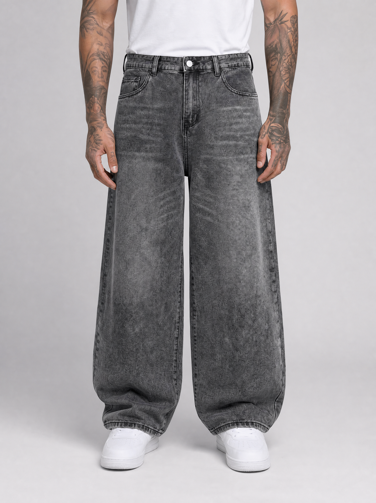 Man wearing oversized baggy jeans in washed denim, front view on a light grey studio background