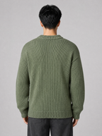 Back view of a sage green drop shoulder knit sweater showing the shoulder line and sleeves
