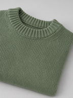 Close up of the ribbed crew neck and knit stitch texture on a sage green sweater