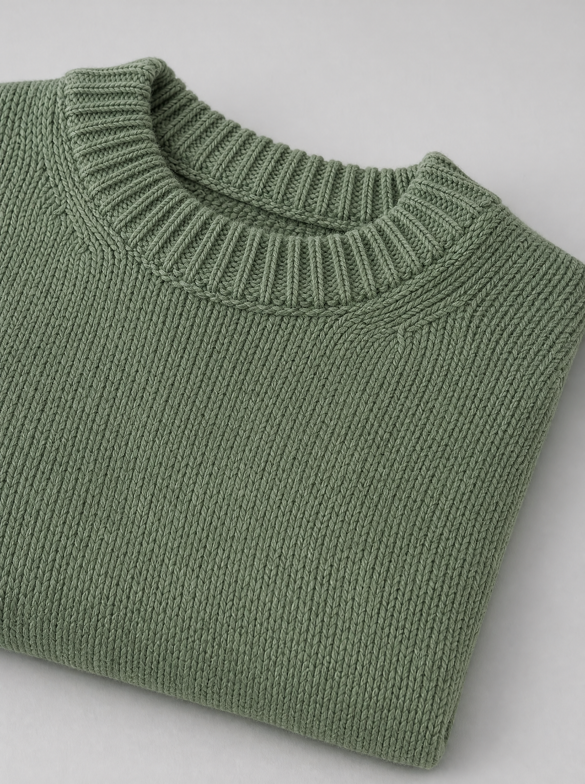 Close up of the ribbed crew neck and knit stitch texture on a sage green sweater