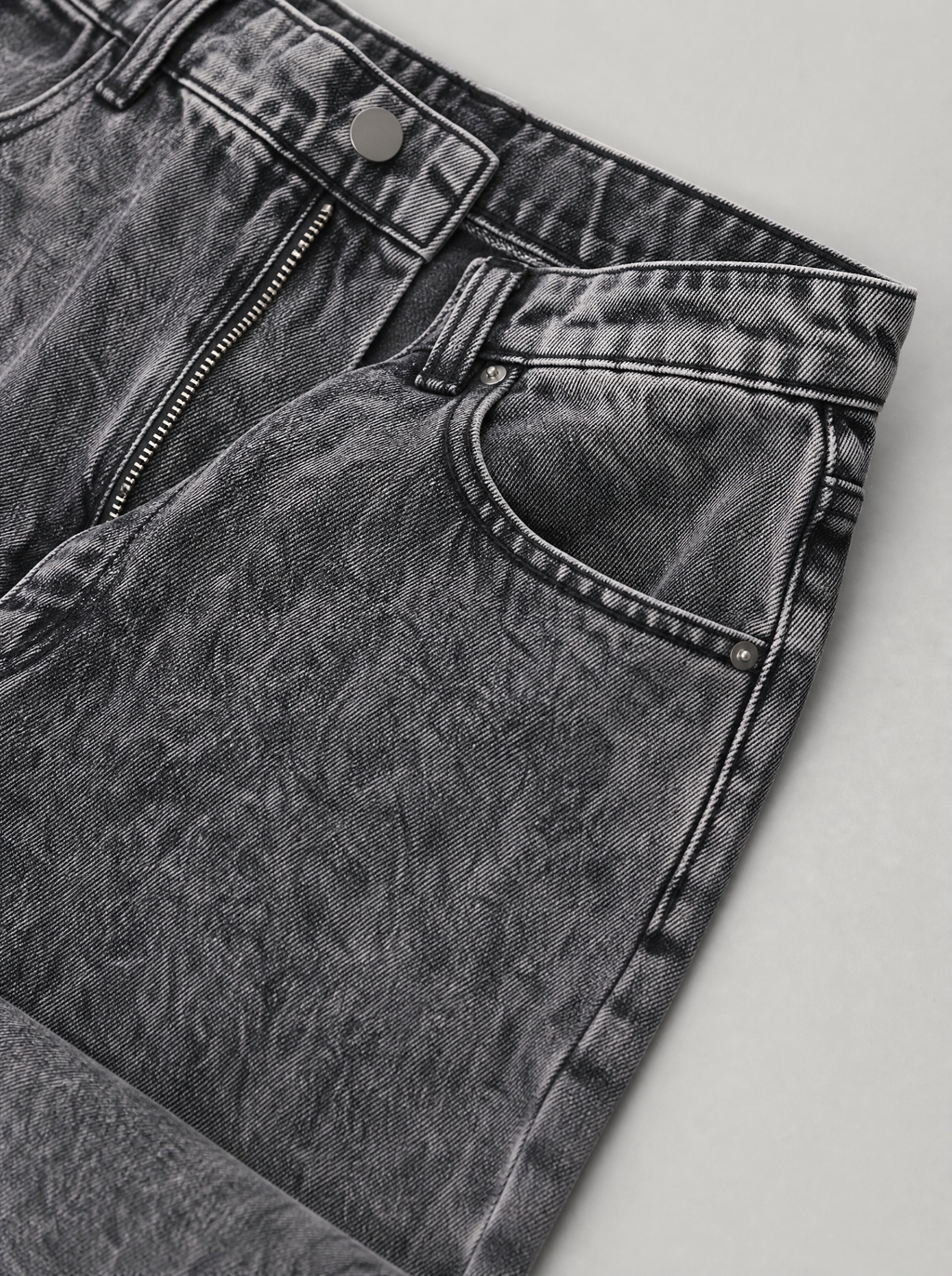 Close up of the waistband, shank button and pocket stitching on smoke grey washed jeans