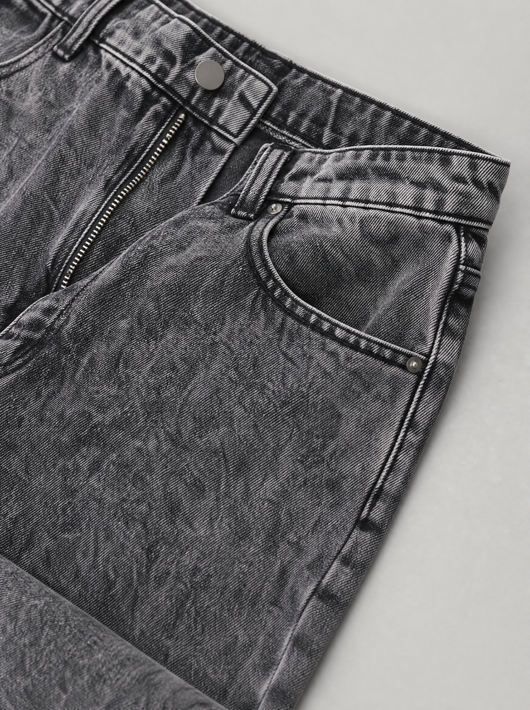 Close up of the waistband, shank button and pocket stitching on smoke grey washed jeans