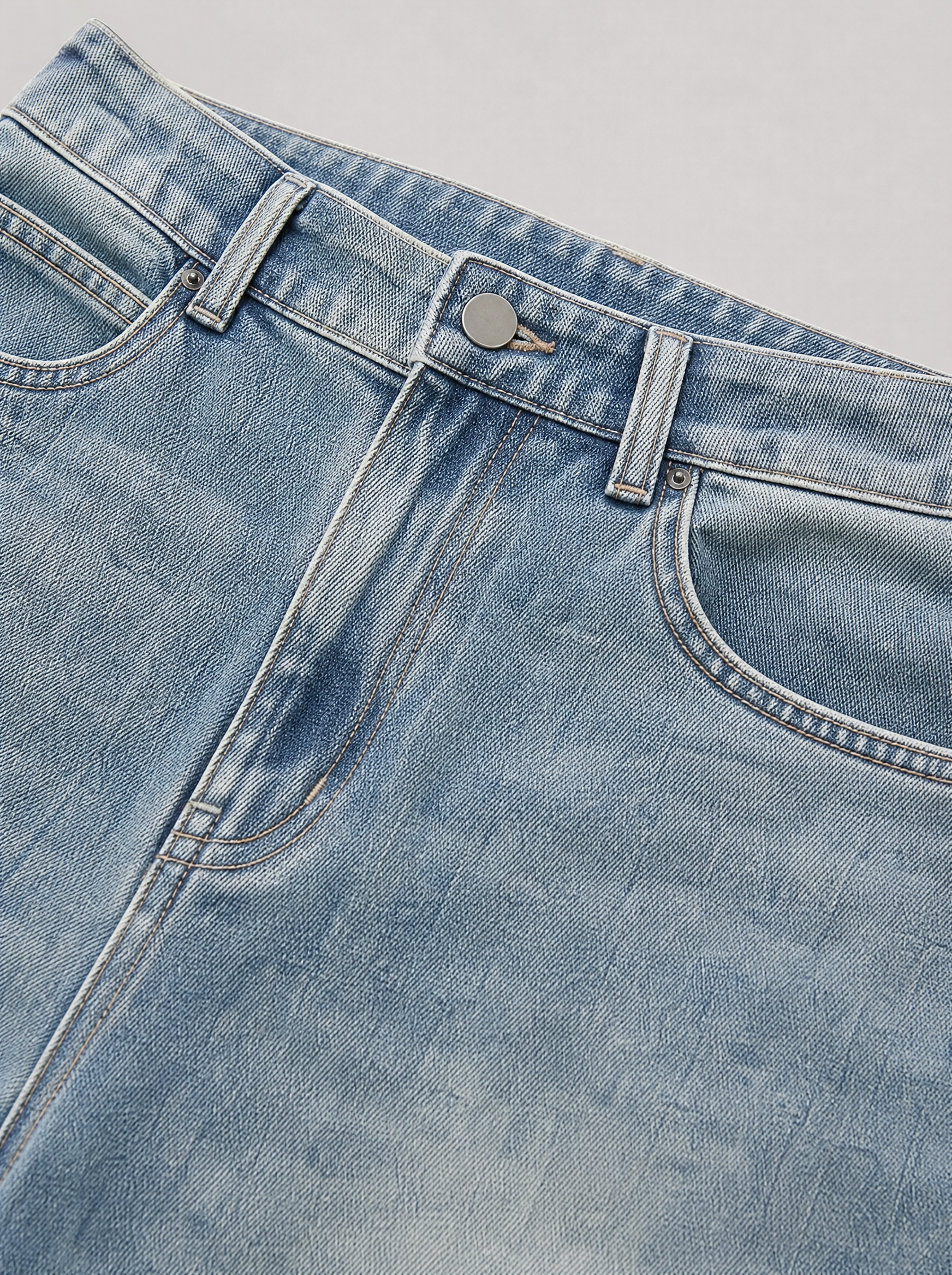 Close up of the waistband, shank button and pocket stitching on vintage blue washed jeans