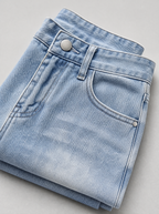 Close up of the waistband, shank button and pocket stitching on washed denim relaxed straight jeans