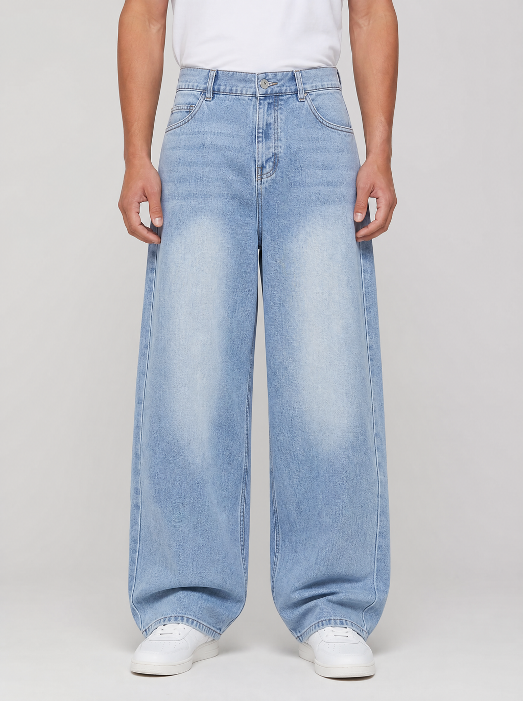 Man wearing washed denim relaxed straight jeans, front view on a light grey studio background