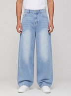 Man wearing washed denim relaxed straight jeans, front view on a light grey studio background