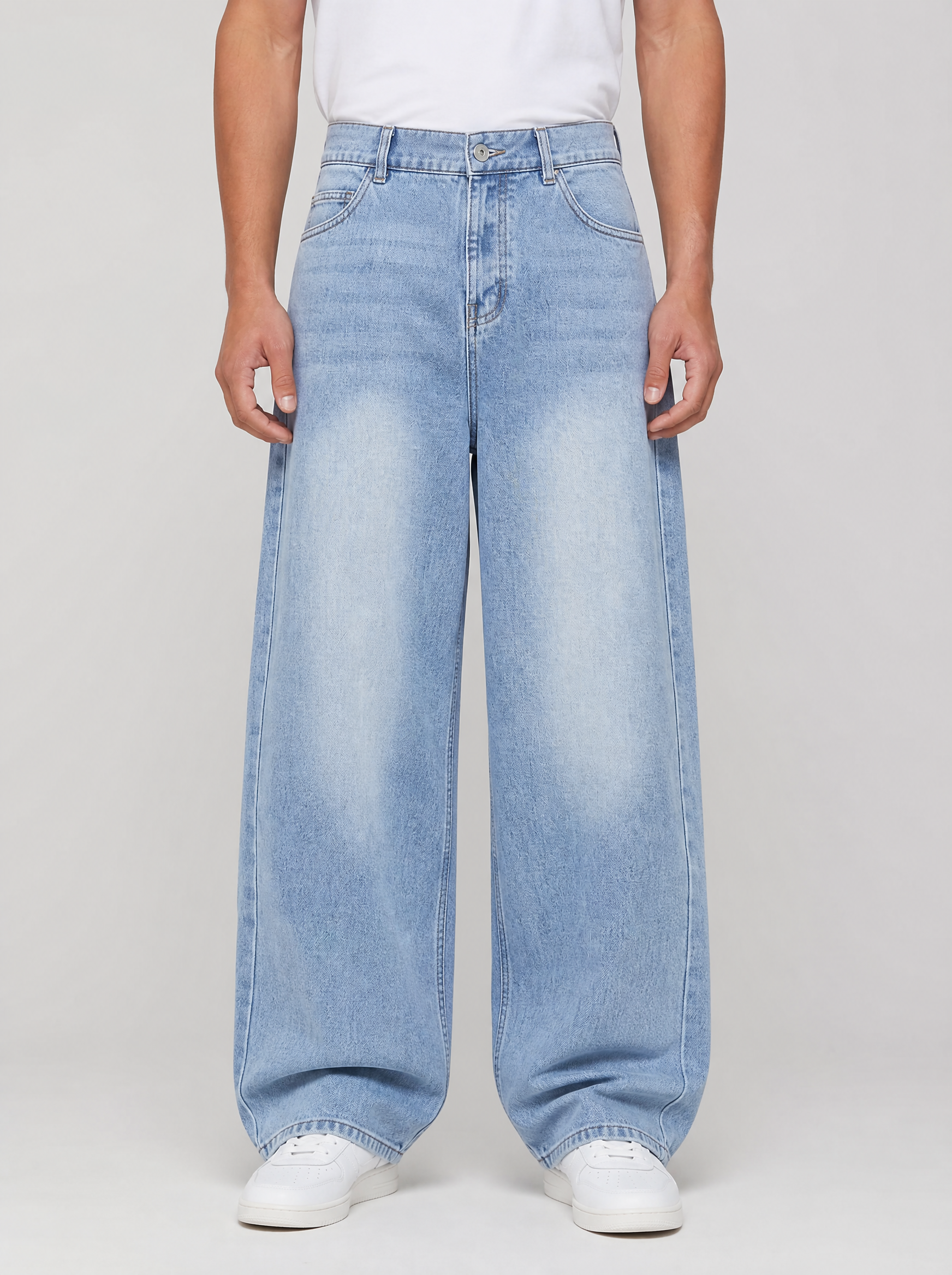 Man wearing washed denim relaxed straight jeans, front view on a light grey studio background