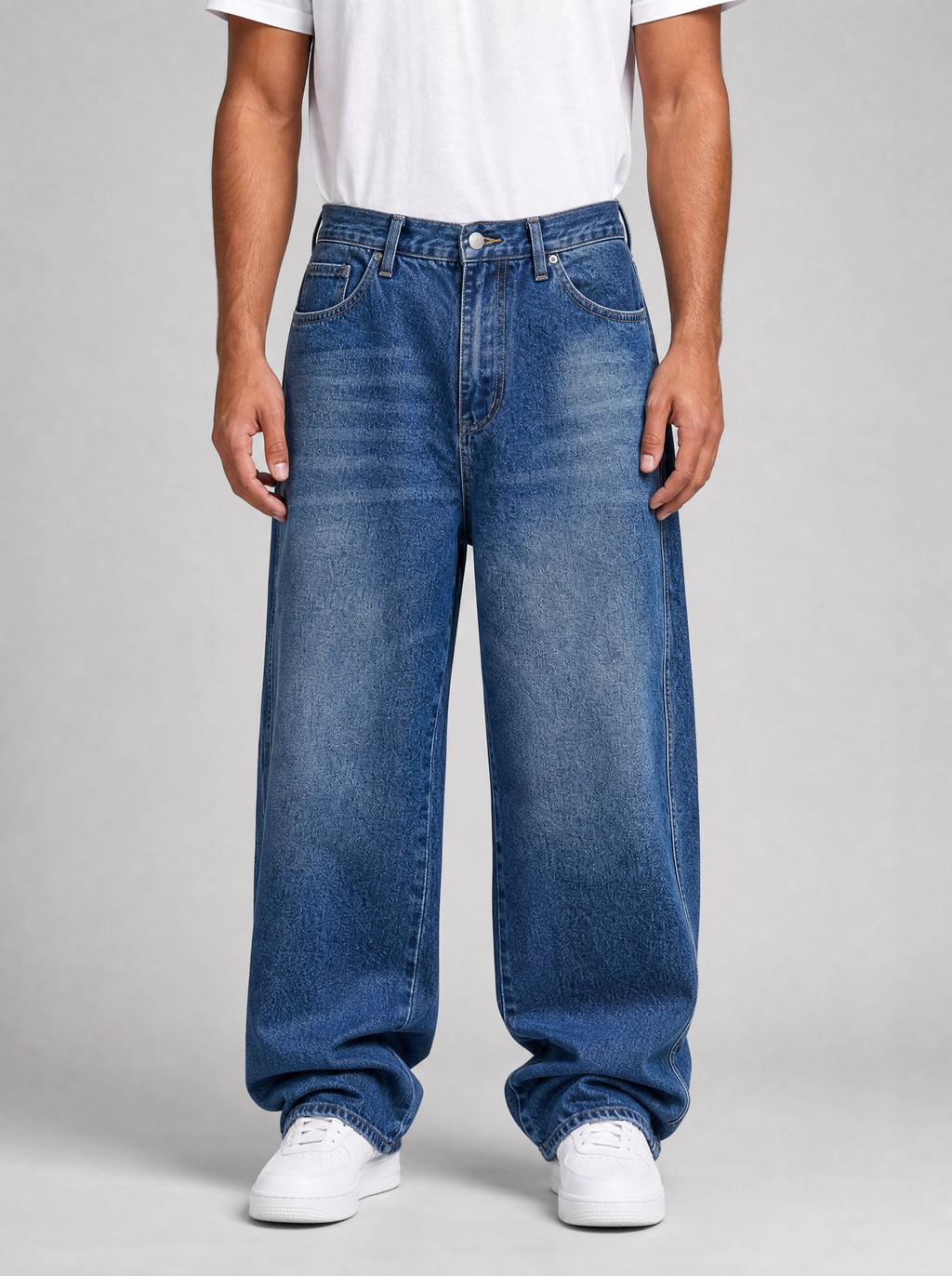 Man wearing whiskered wash loose straight jeans, front view on a light grey studio background