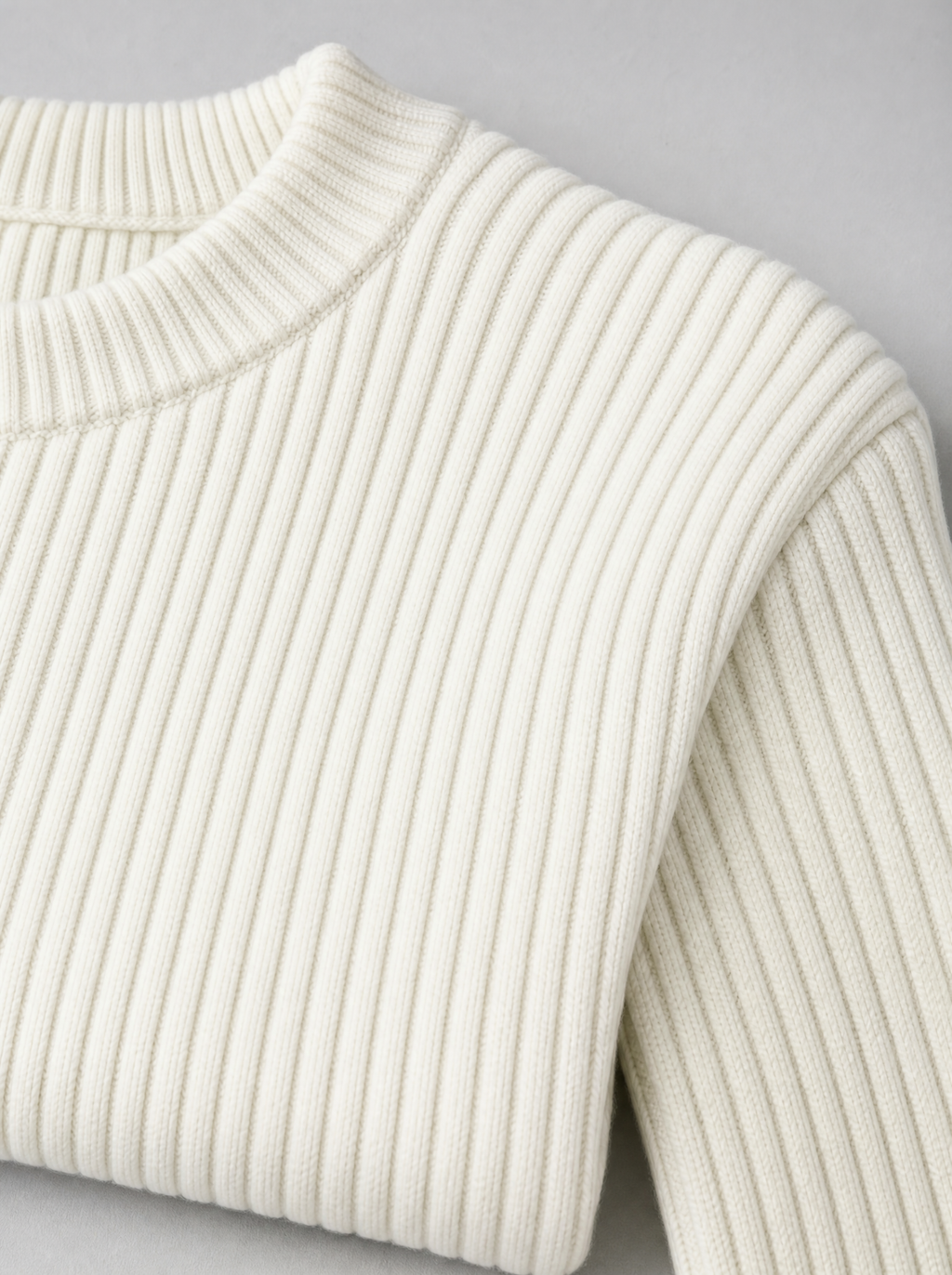 Close up of the ribbed crew neck and vertical rib texture on a white knit sweater